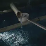 water flowing through brown wooden pipe into surface